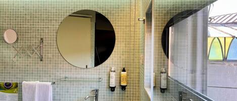 A bathroom with two sinks, a round mirror, and a shower area.