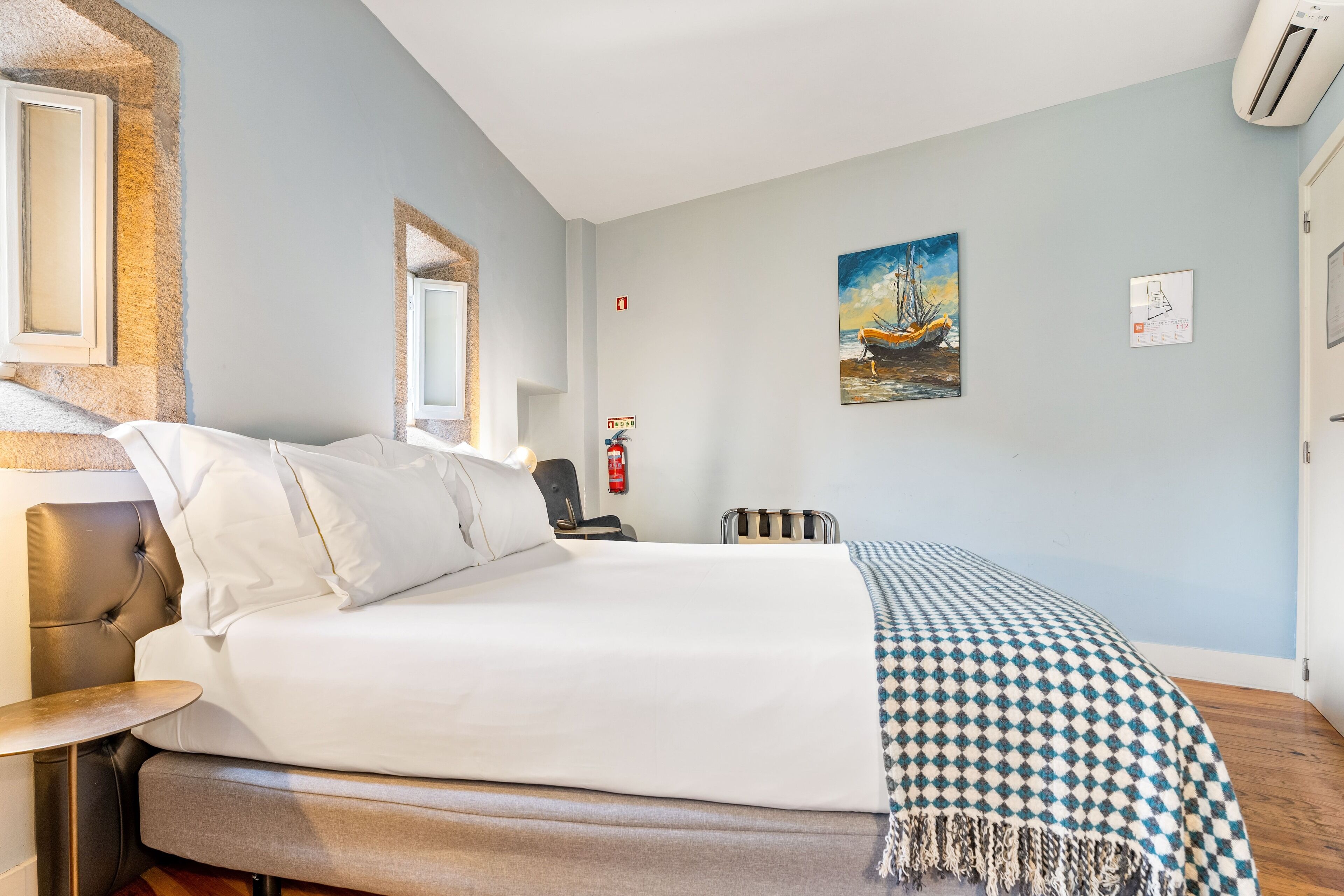 A neatly made bed with white linens, a checkered throw blanket, and a headboard.