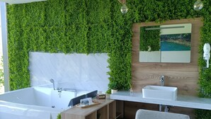 A modern bathroom with a large bathtub, a sink, and a mirror. - Dobau Village (Vieira do Minho)