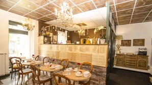 Un espace repas avec des tables et des chaises rondes, un lustre et un mur où sont affichés les menus.