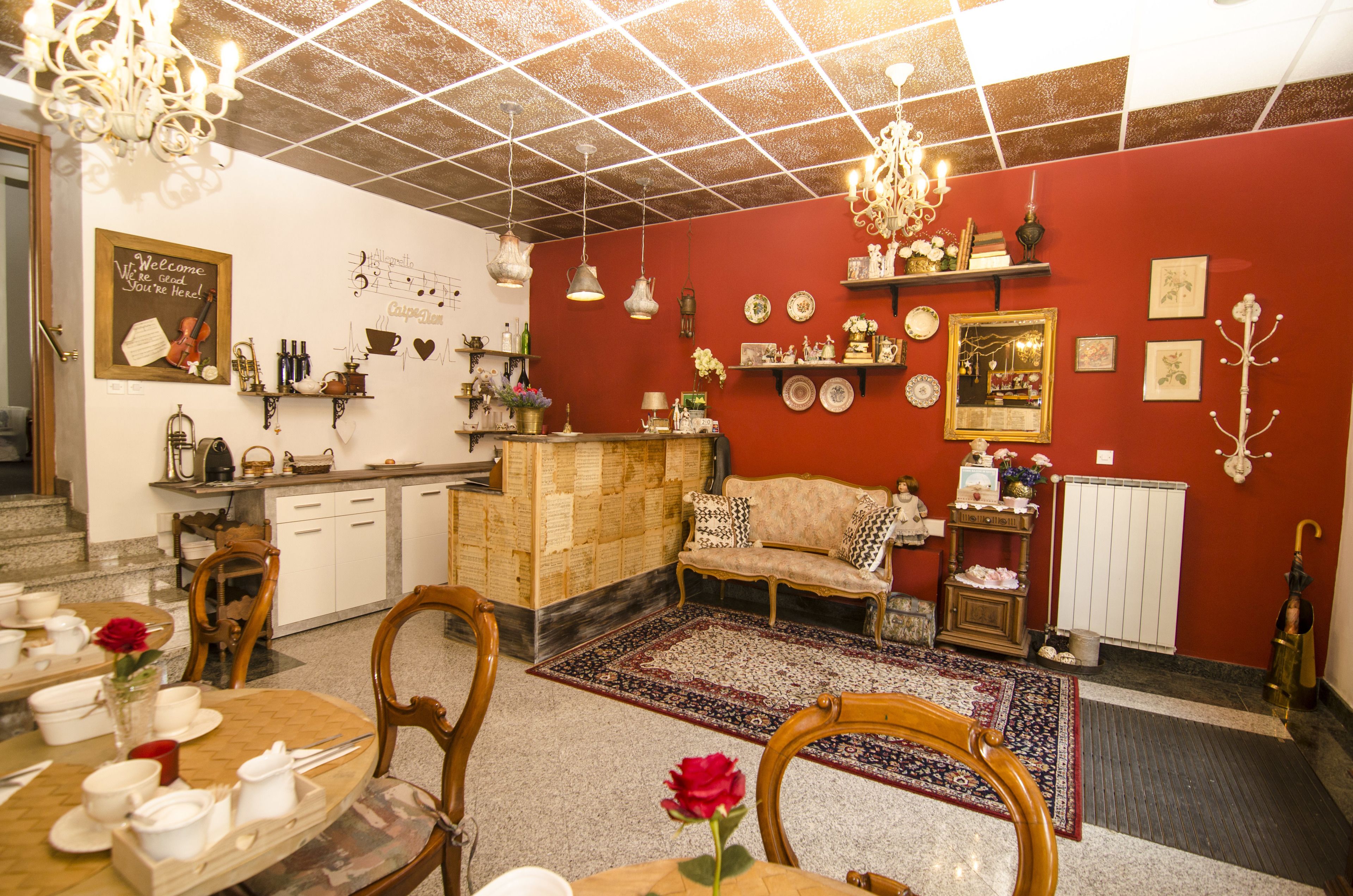 Un coin repas avec une table en bois dressée pour le repas, un canapé et un mur rouge agrémenté de diverses décorations.