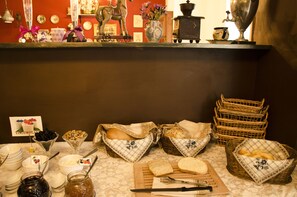 Mesa de desayuno tipo buffet con diversos alimentos y utensilios.