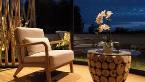 A modern room with a wooden chair and a glass table with a wooden base. - Clos Marie (Iguerande)