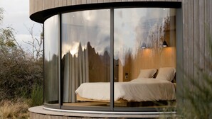 A modern bedroom with a glass enclosure, a bed, and a view of the outdoors. - Clos Marie (Iguerande)