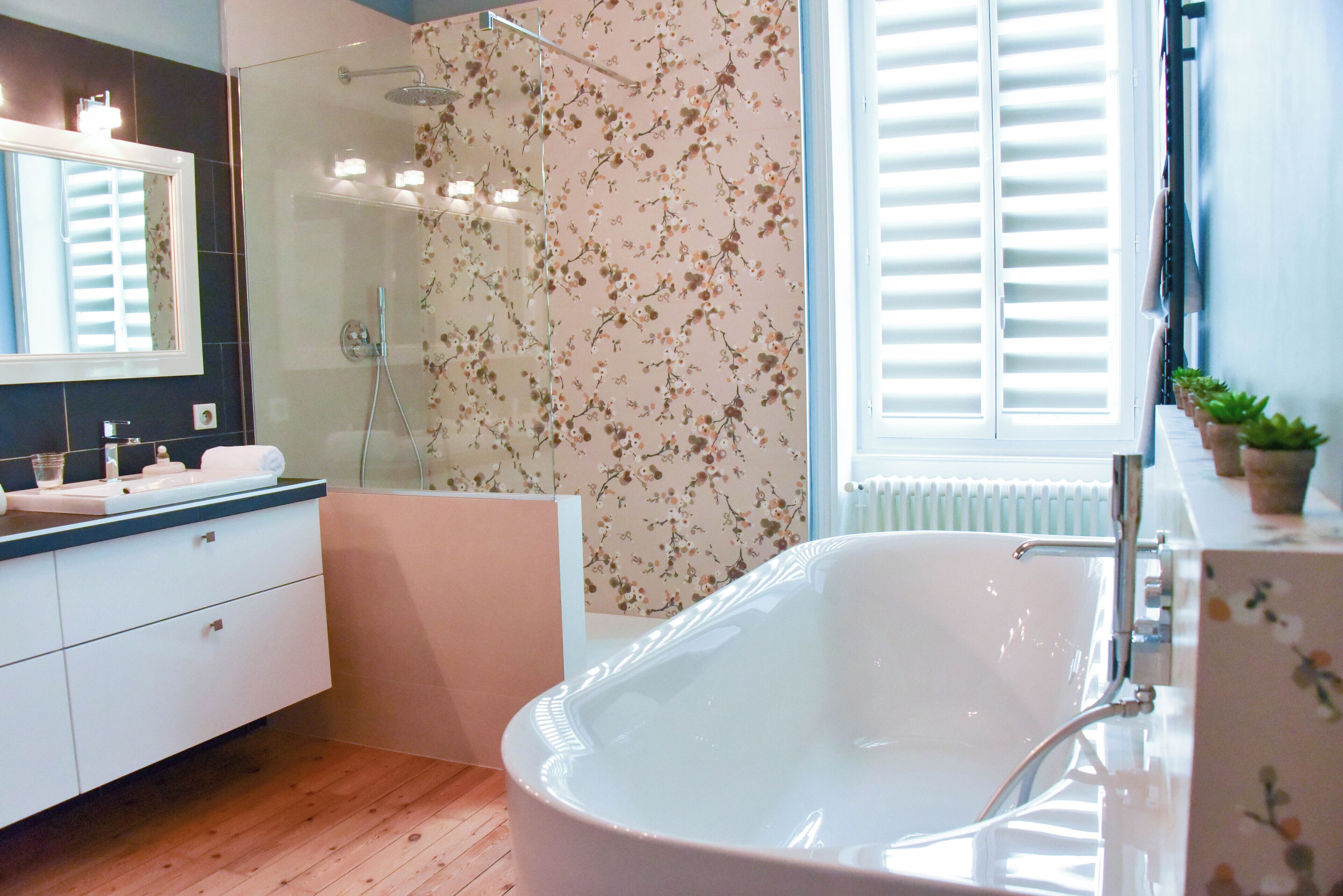 A modern bathroom with a freestanding bathtub, a glass-enclosed shower, and a large mirror.