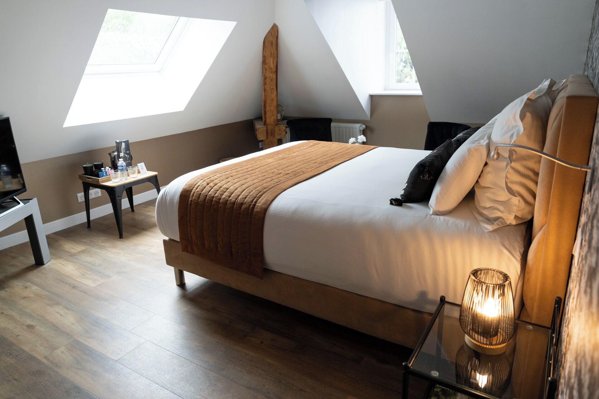 A bedroom with a large bed, a bedside table, a lamp, and a window.