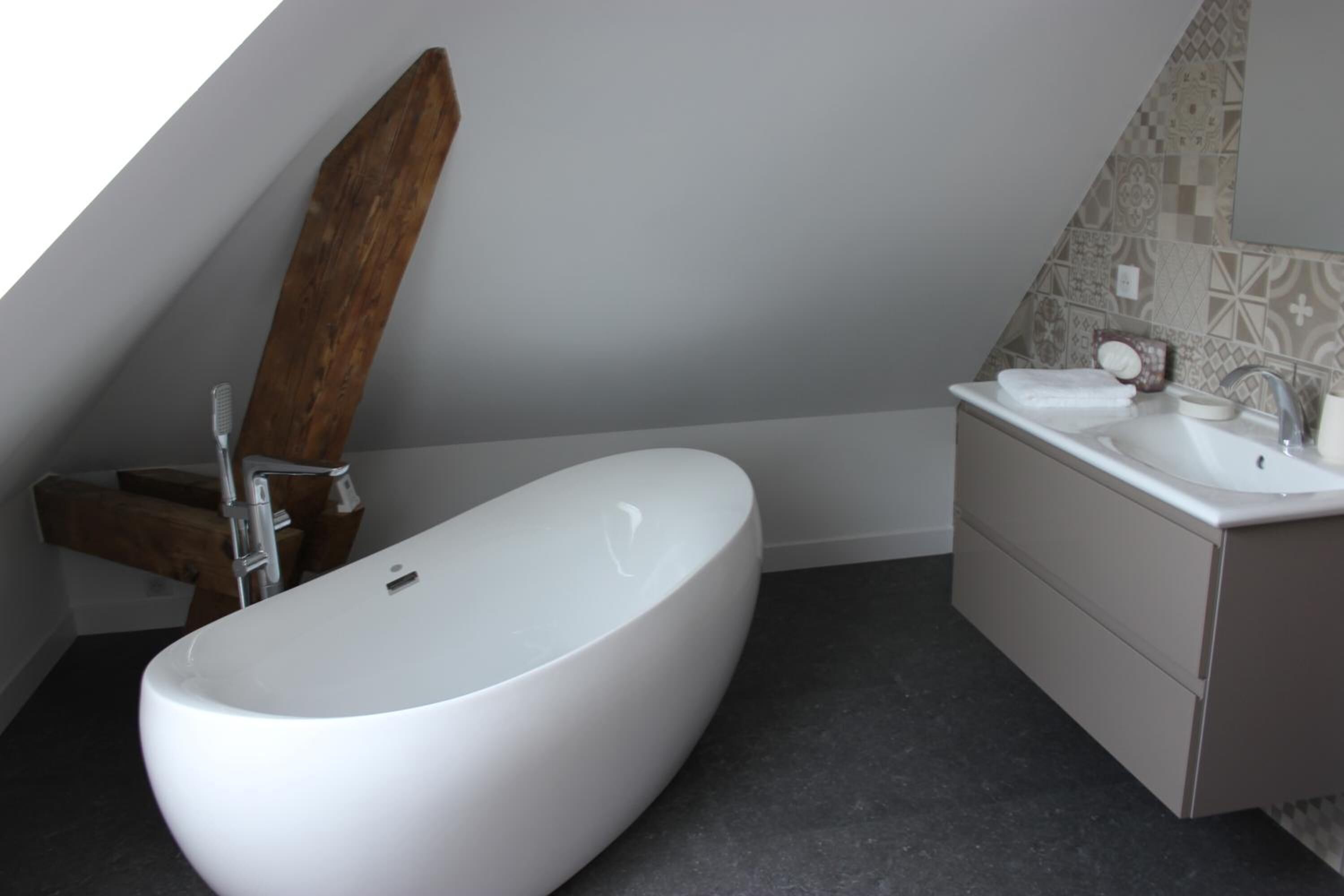 A modern bathroom with a freestanding bathtub, a vanity with a sink, and a wooden shelf.