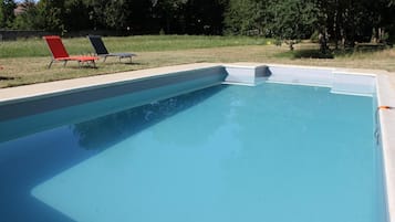 Una piscina al aire libre de temporada, sillones reclinables de piscina