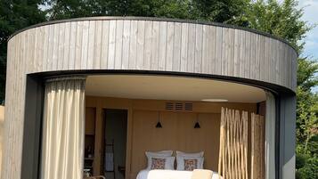 Una estructura circular de madera con una cama, cortinas y un pequeño rincón de descanso.
