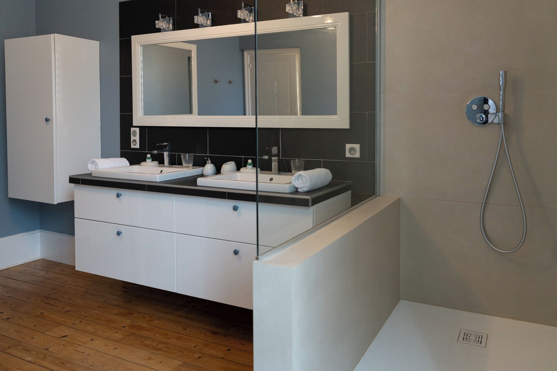 Un bagno moderno con due lavandini, un grande specchio e una doccia.