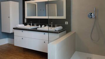 Un bagno moderno con due lavandini, un grande specchio e una doccia.