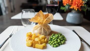 A plate with a dumpling, diced potatoes, and peas, accompanied by a fork and knife on a napkin.