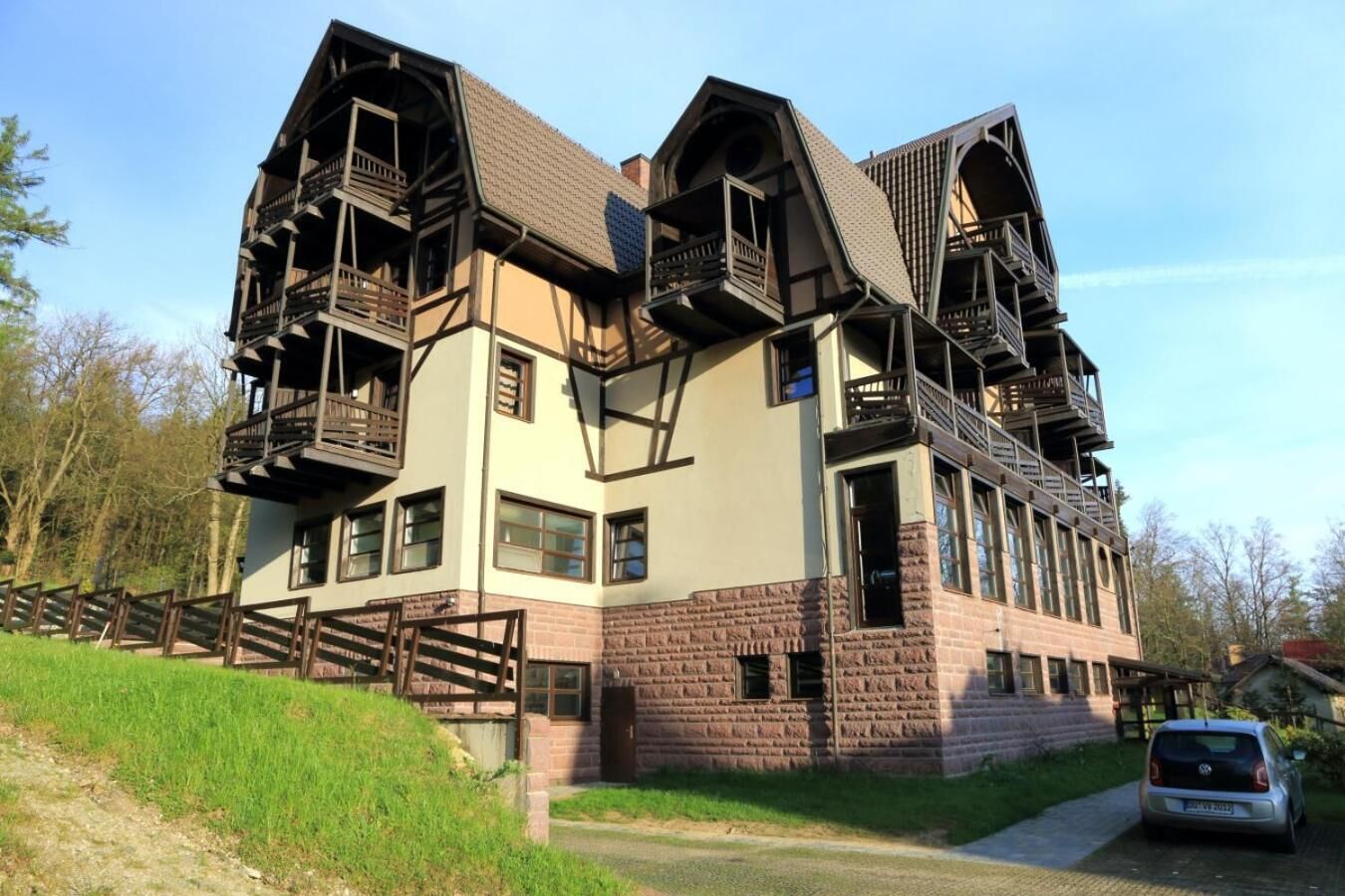 Un edificio grande de varios pisos con un diseño arquitectónico único, que destaca por amplios balcones de madera y una fachada de ladrillo.