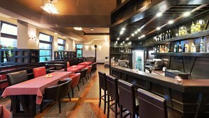 Un restaurante con varias mesas, una zona de bar y una cocina al fondo.