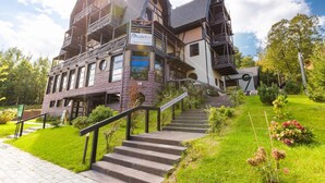 Un hotel de varios pisos con restaurante, que destaca por su diseño arquitectónico único, con balcones y una escalera que conduce a la entrada.