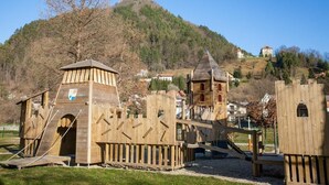 A wooden play structure with a castle-like design, including a tower and ramp. - Villa Home & Garden Lasko (Lasko)