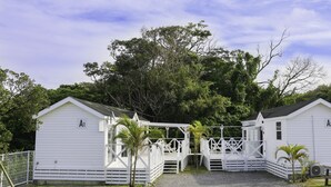 Two white cabins with A1 and A2 signs, surrounded by trees and a clear sky. - Cottage Star House Nakijin (Nakijin)