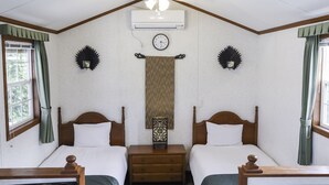 A hotel room with two single beds, a ceiling fan, an air conditioning unit, a clock, and decorative wall sconces. - Cottage Star House Nakijin (Nakijin)