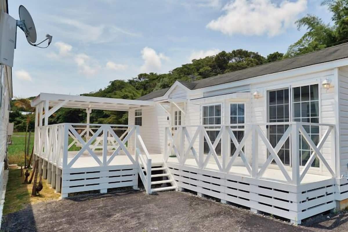 Un bâtiment en bois peint en blanc, doté d’un porche et d’une zone abritée.