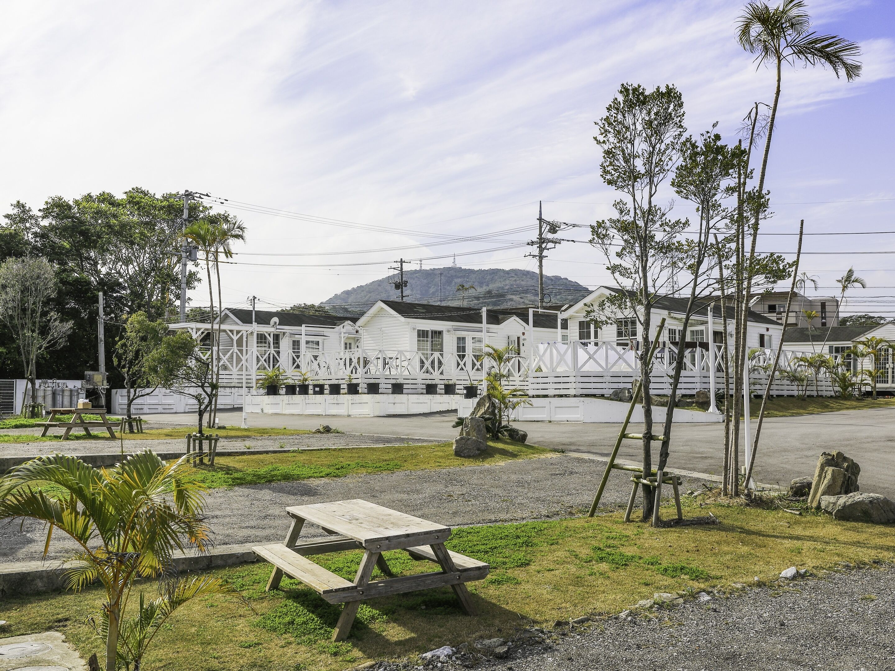 A row of white cabins with a picnic table in the foreground.