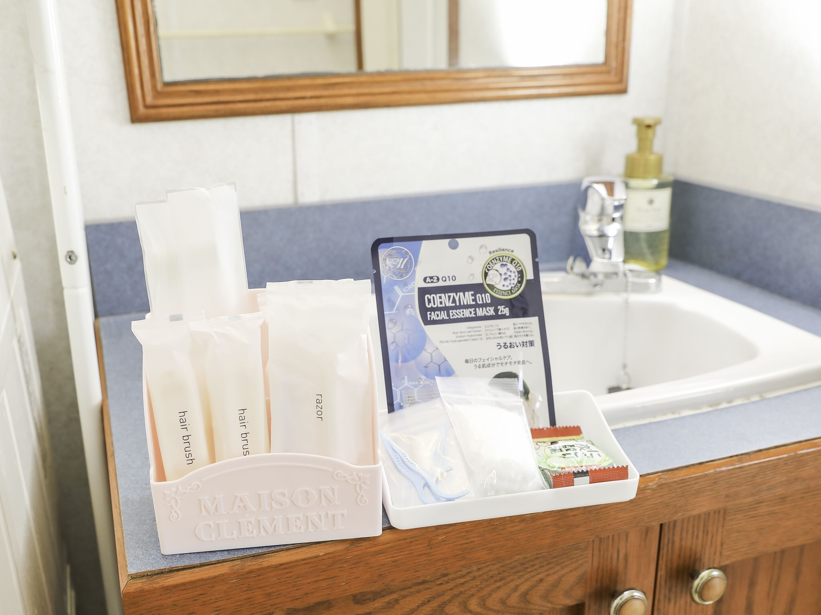 Un ripiano del bagno con articoli da toilette, tra cui uno spazzolino, una maschera viso e altri prodotti per la cura personale.
