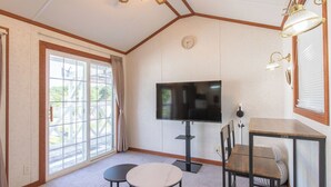 A room with a TV, two small tables, a chair, a ceiling fan, and a window with curtains. - Cottage Star House Nakijin (Nakijin)