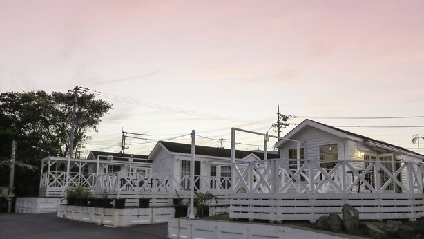 A row of white cabins with a white fence in front, set against a pink sky. - Cottage Star House Nakijin (Nakijin)