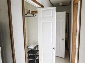 A hallway with a white door, a coat rack, and a black metal shelf unit. - Cottage Star House Nakijin (Nakijin)