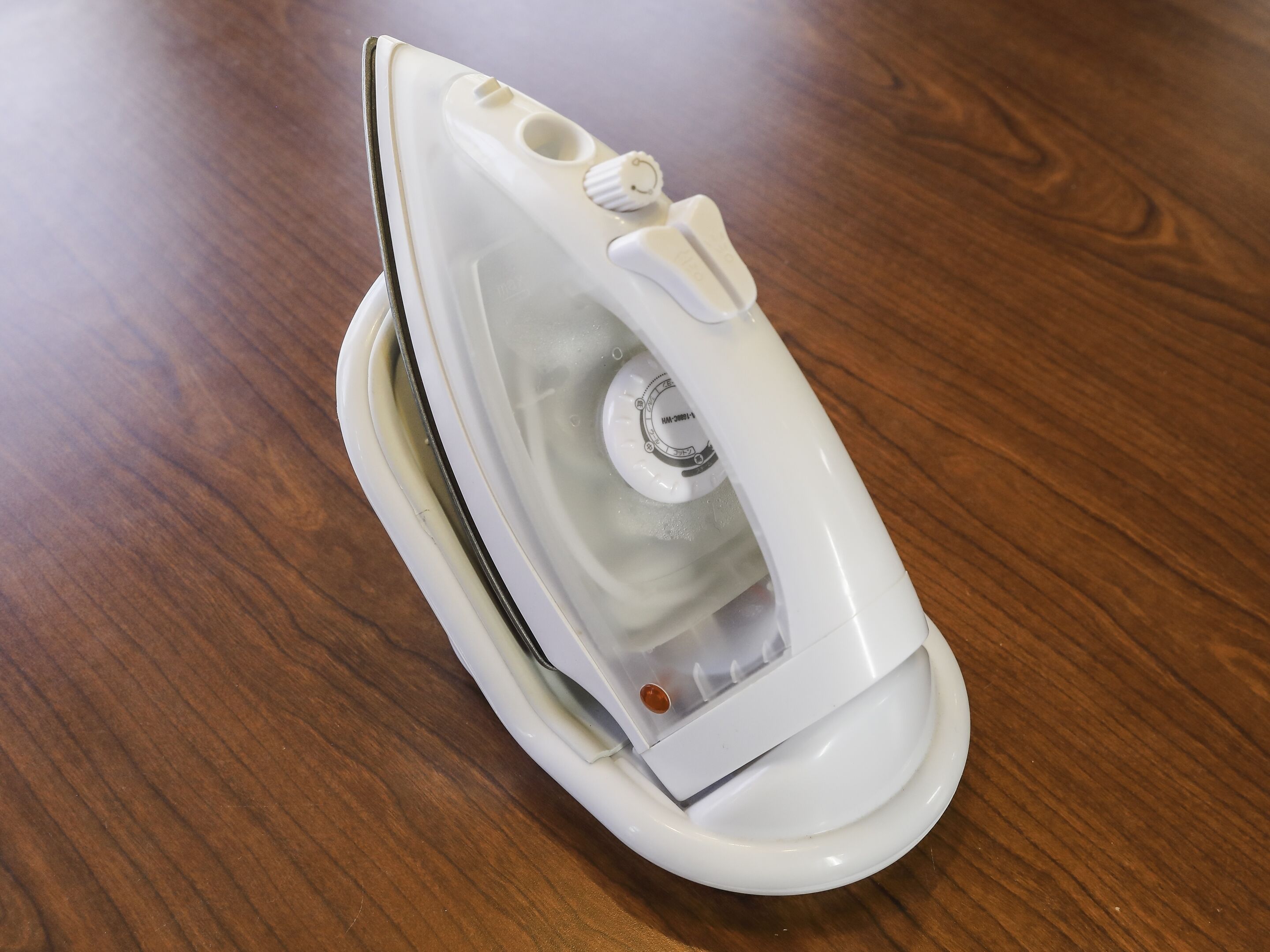 A white iron on a wooden table.