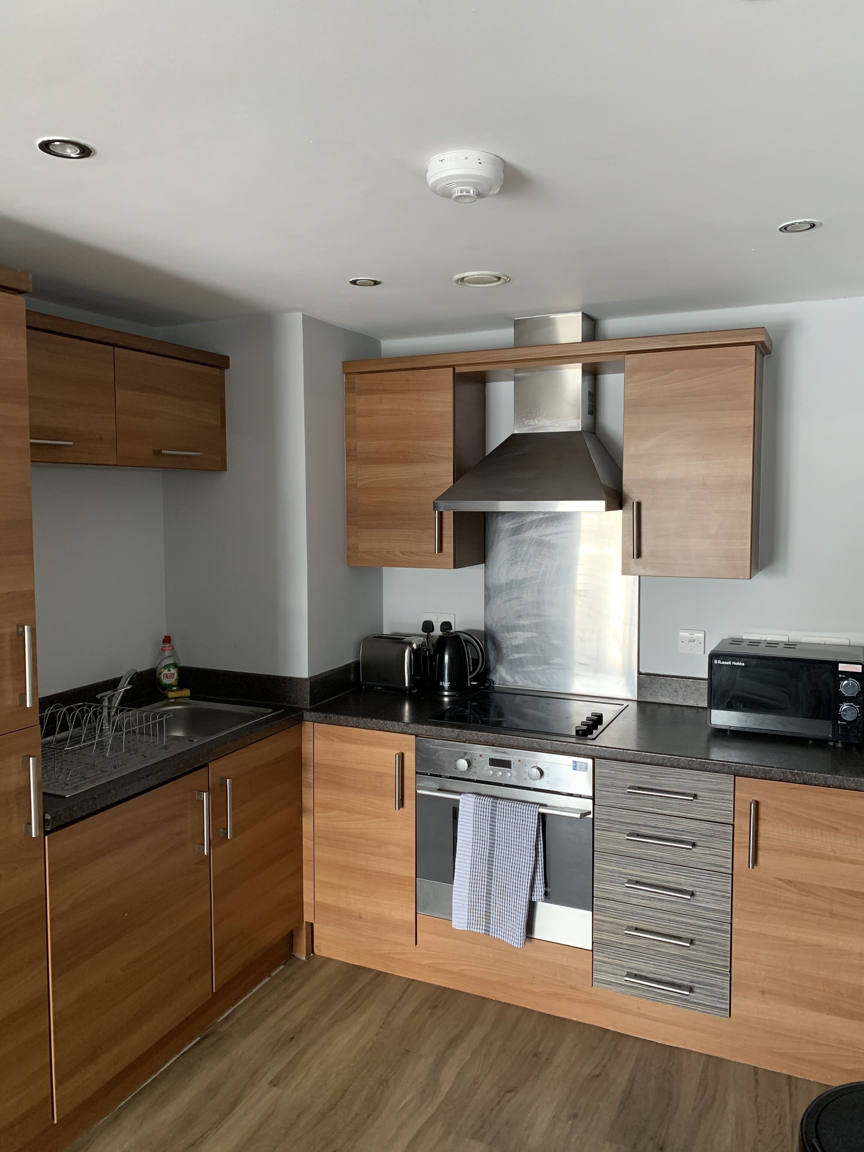 A modern kitchen with wooden cabinets, stainless steel appliances, and a black countertop.