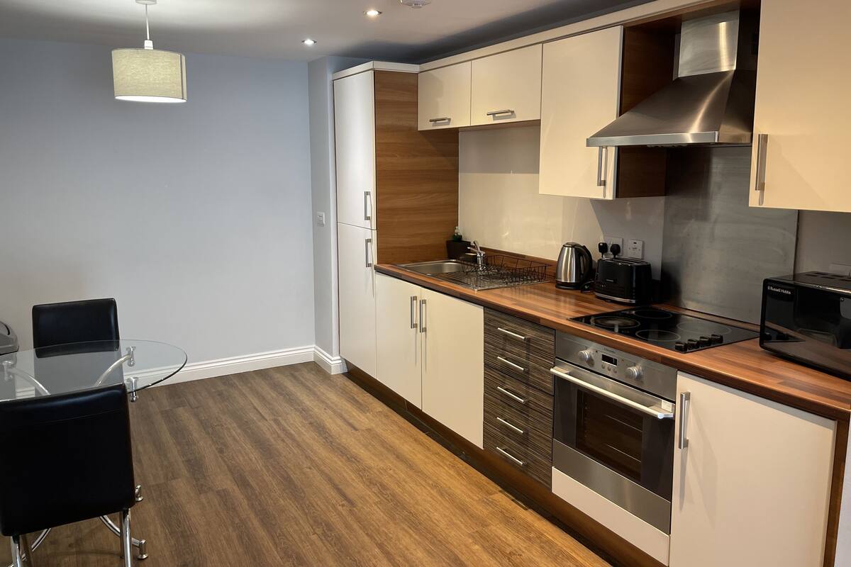 Une cuisine moderne avec des meubles en bois, des appareils électroménagers en acier inoxydable et une table à manger en verre.