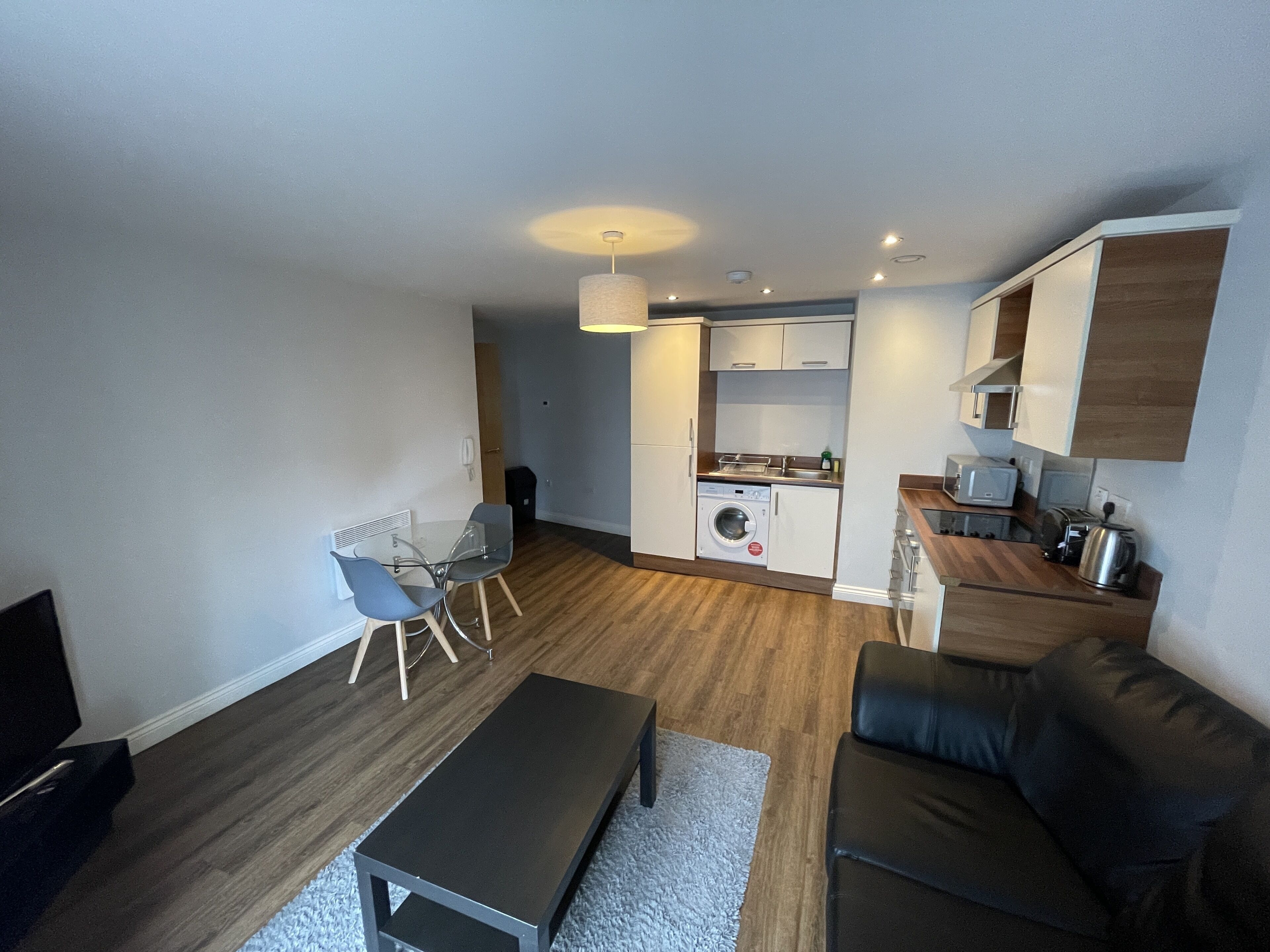 Ein gemütlicher Wohnraum mit Essbereich, einer Couch, einem Couchtisch, einer Waschmaschine, einer Mikrowelle und einem Toaster.