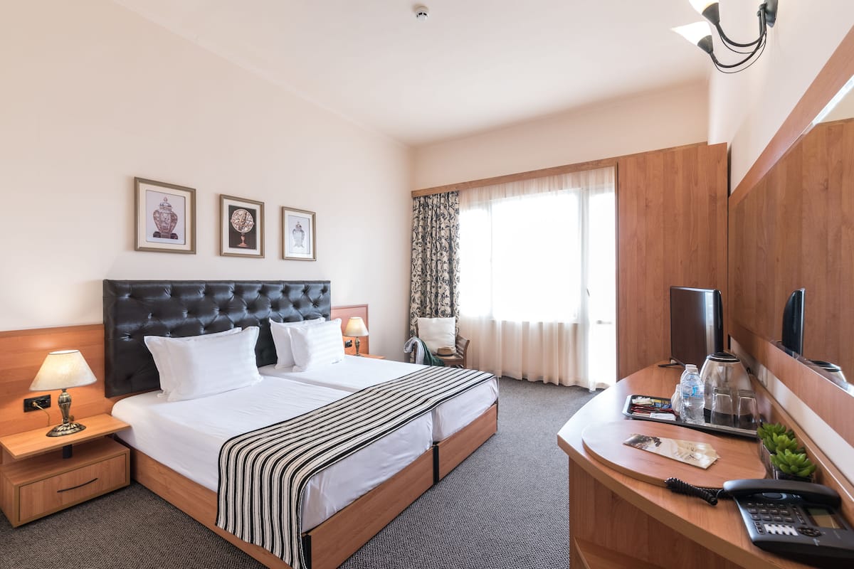 Habitación de hotel con una cama grande, un escritorio, un teléfono y una televisión.