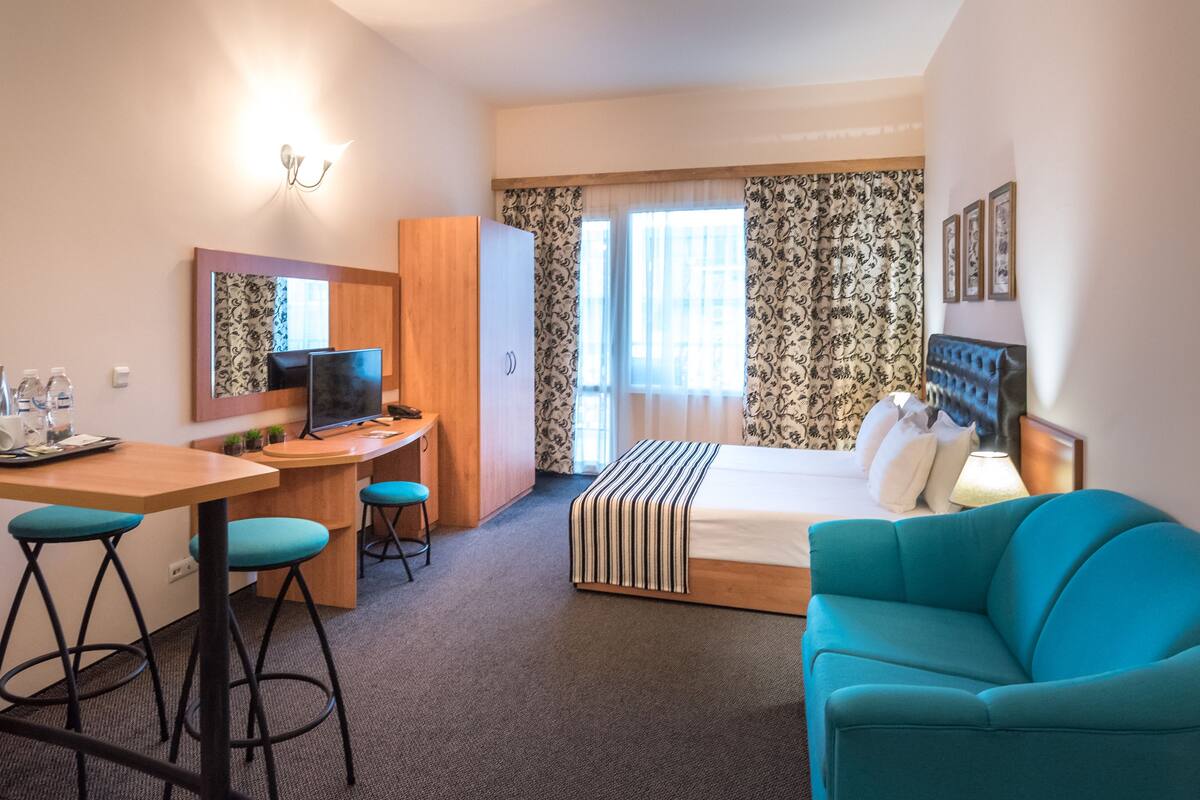 Una habitación de hotel con una cama, un escritorio con una silla, un televisor y un sofá.