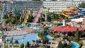 Un parc aquatique doté de nombreux toboggans et d’une piscine entourée de chaises longues et de parasols.