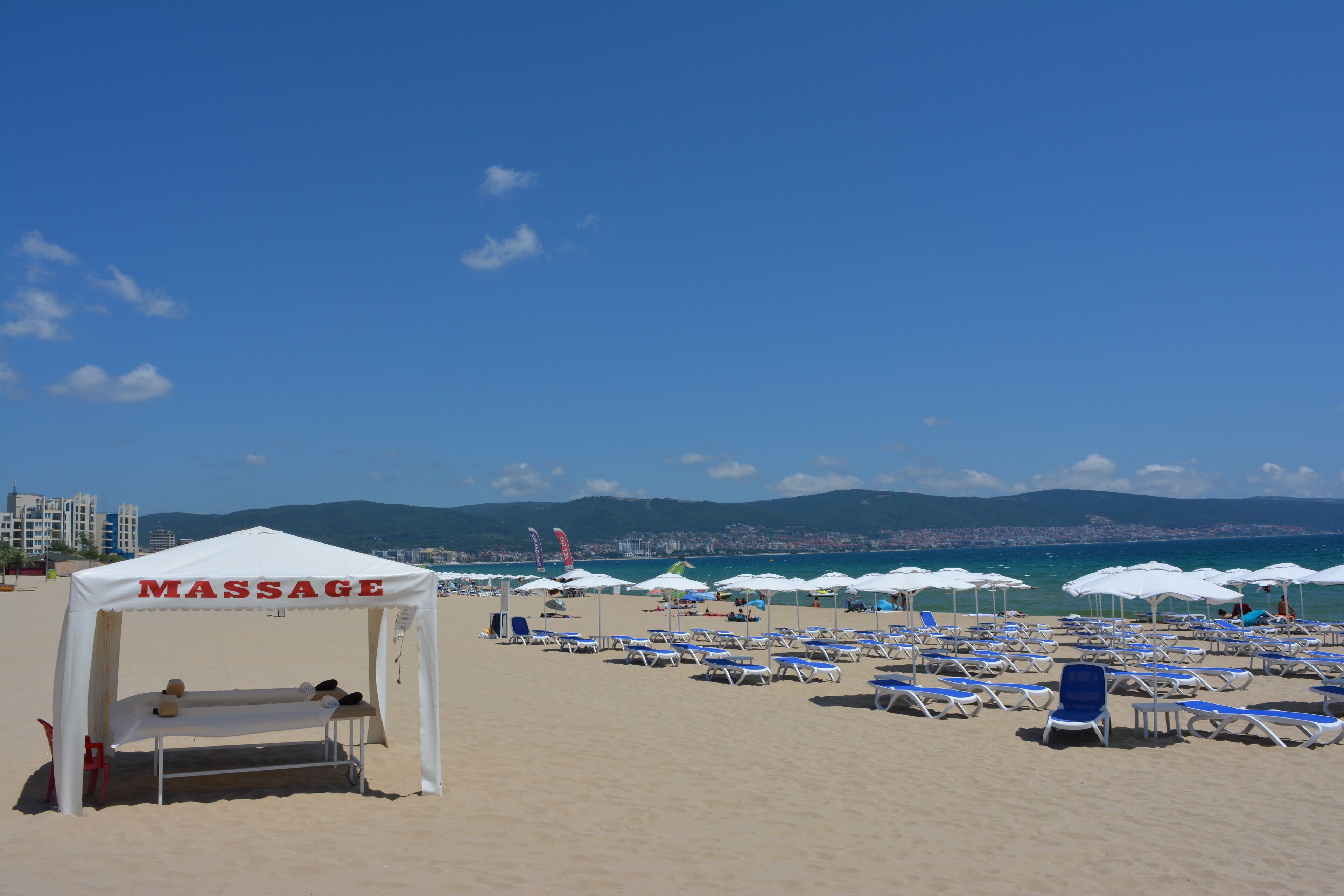 Ein Strand mit einem Massagezelt und mehreren Sonnenschirmen.