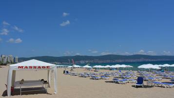 Ein Strand mit einem Massagezelt und mehreren Sonnenschirmen.