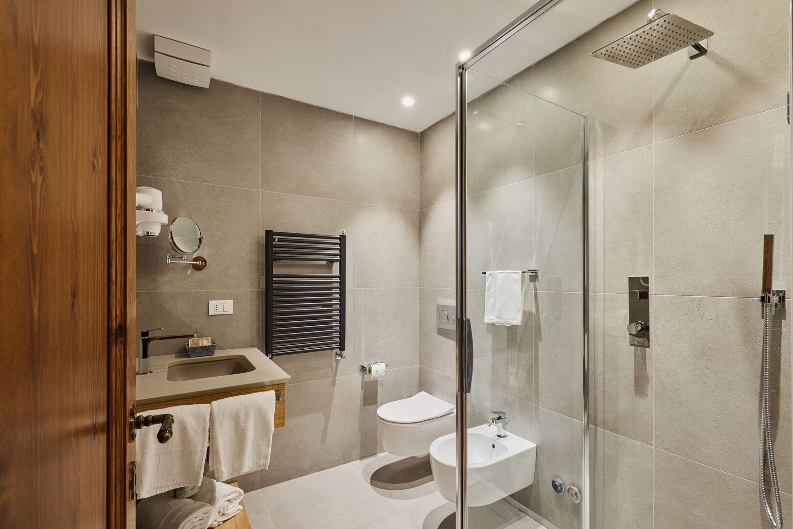 A modern bathroom with a glass shower enclosure, a sink, and a toilet.