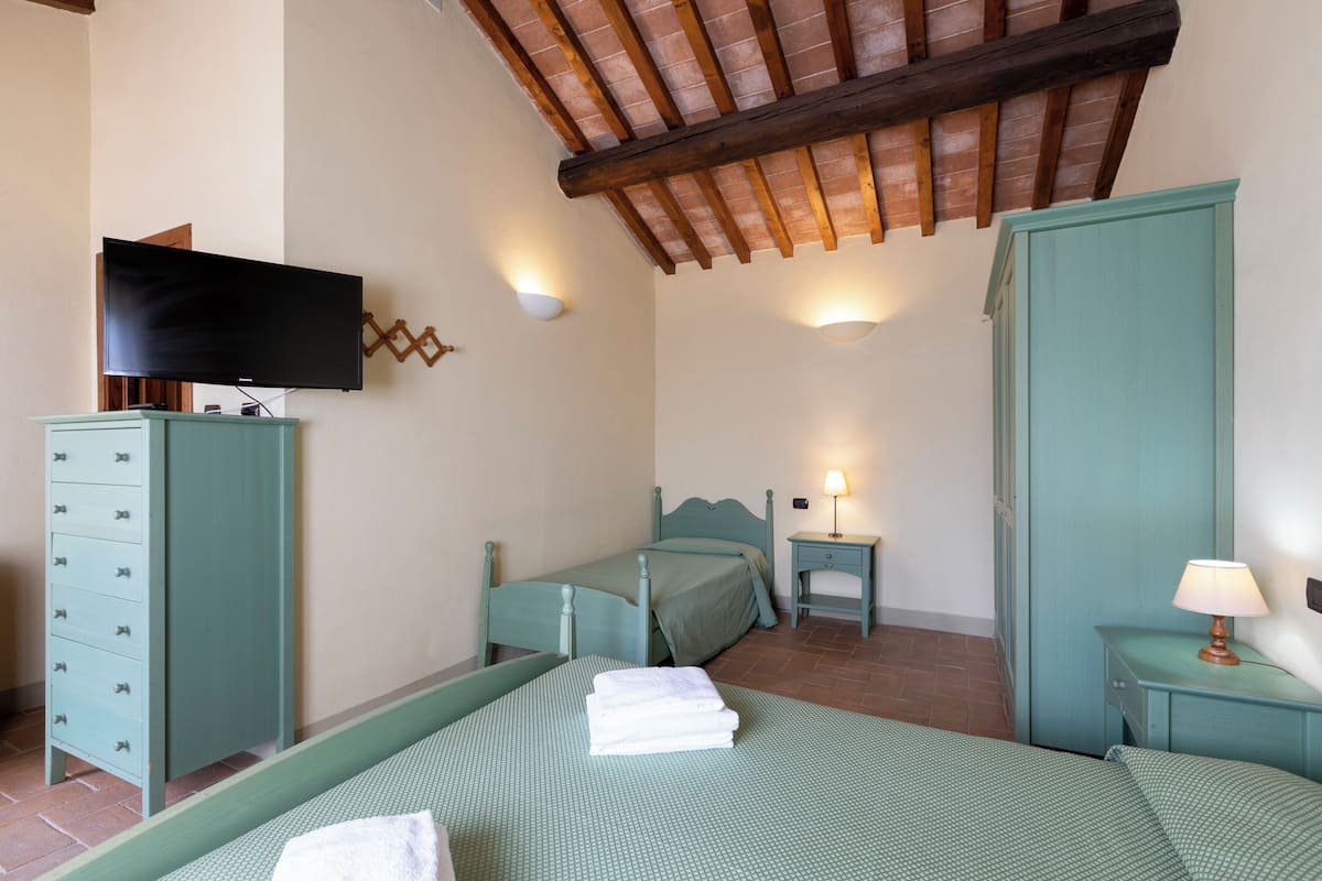 Un dormitorio con dos camas, televisión, cómoda y mesita de noche con lámpara.