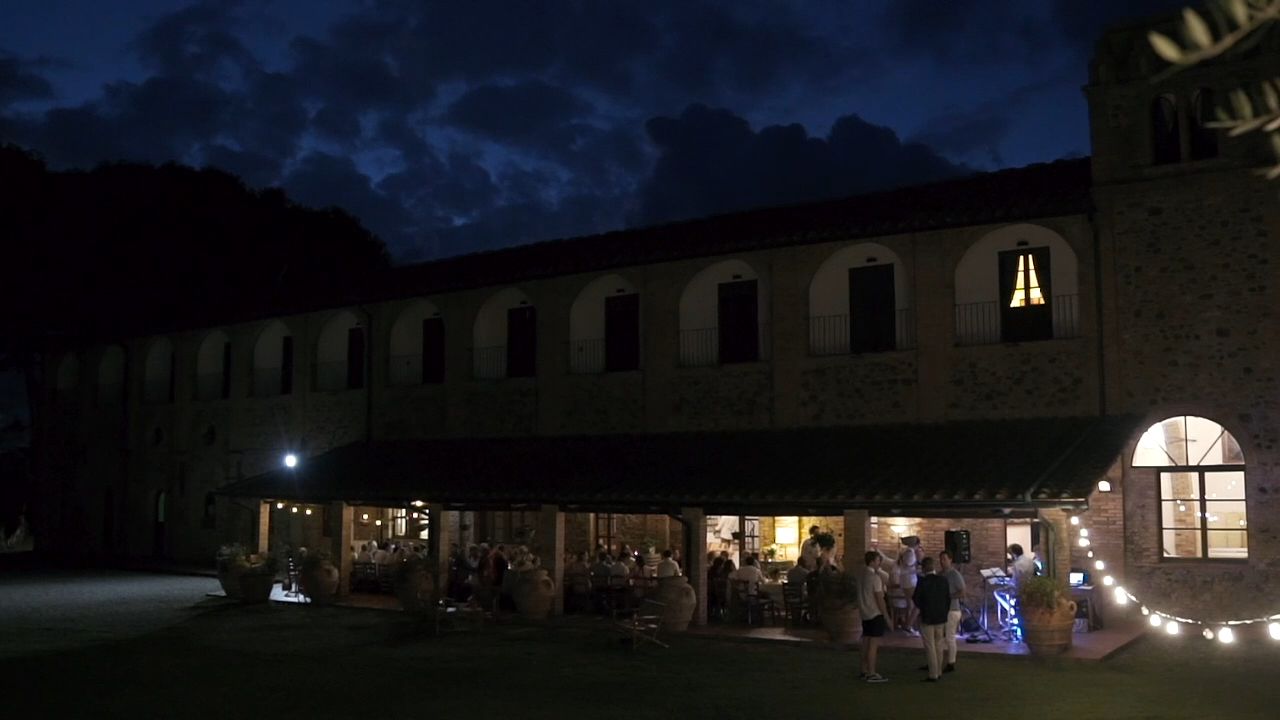A building with multiple arched windows and a covered outdoor area with tables and chairs.