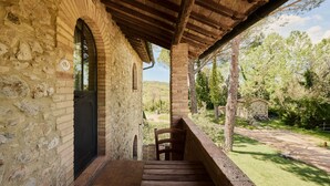 A stone building with a wooden staircase leading to a covered porch. - UNA Hotels Monterufoli Wine Country (Monteverdi Marittimo)