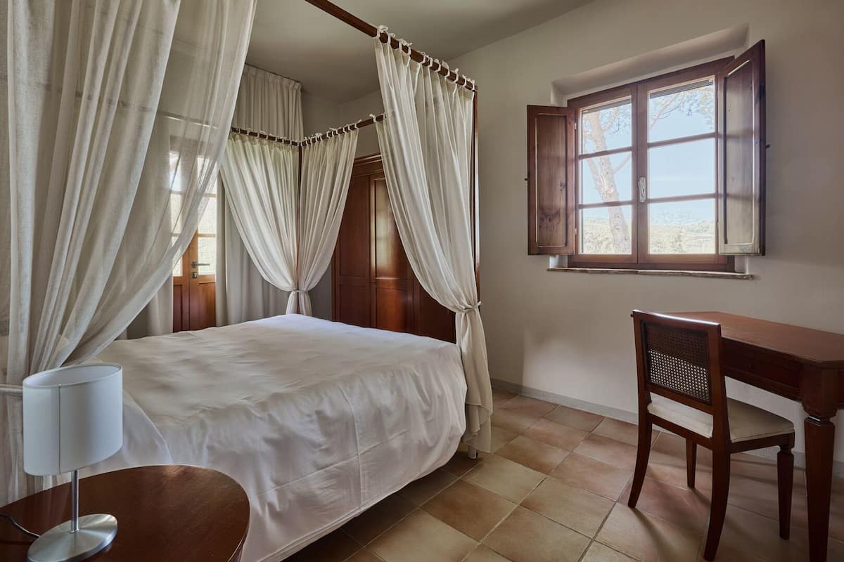Un dormitorio con cama con dosel, un escritorio y una silla.