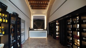 A wine cellar with a reception desk, wine racks, and a view of vineyards. - UNA Hotels Monterufoli Wine Country (Monteverdi Marittimo)