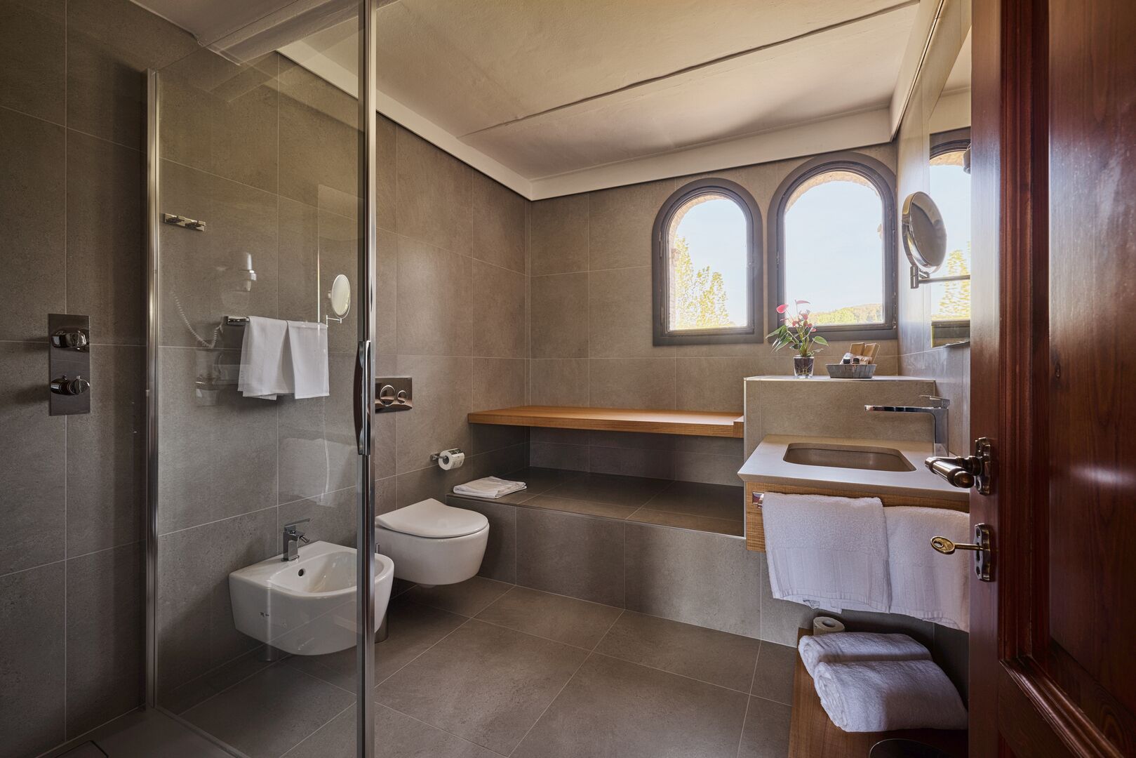 Ein modernes Badezimmer mit Duschkabine aus Glas, Toilette, Bidet und Waschtisch mit Waschbecken und Spiegel.