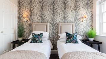 A hotel room with two beds, zebra-striped wallpaper, bedside lamps, and potted plants.