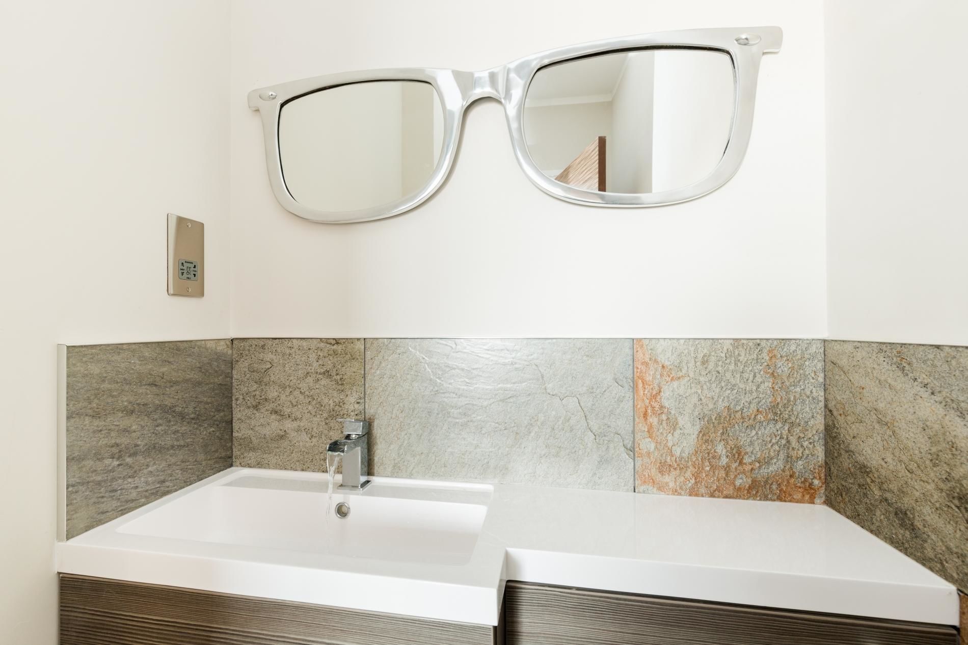 A bathroom with a large mirror, a sink, and a tiled backsplash.