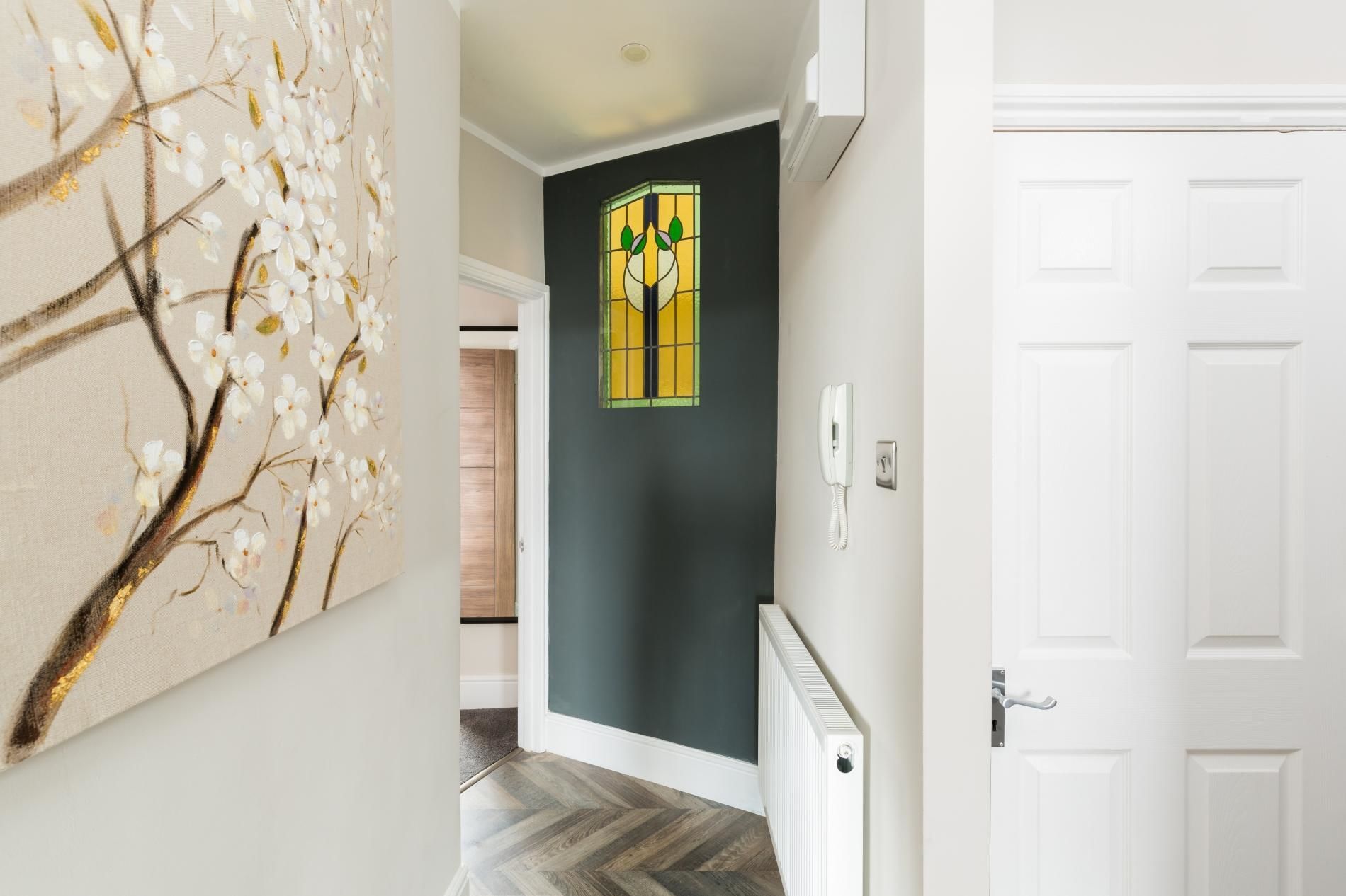A hallway with a white door, a radiator, and a wall-mounted phone.