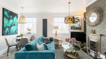 A modern living room with a teal sofa, a fireplace, and a large abstract painting.
