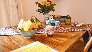 A wooden table with a bowl of fruit, a vase with flowers, a bottle, and a menu. - Sunrise Luxury (Naples)