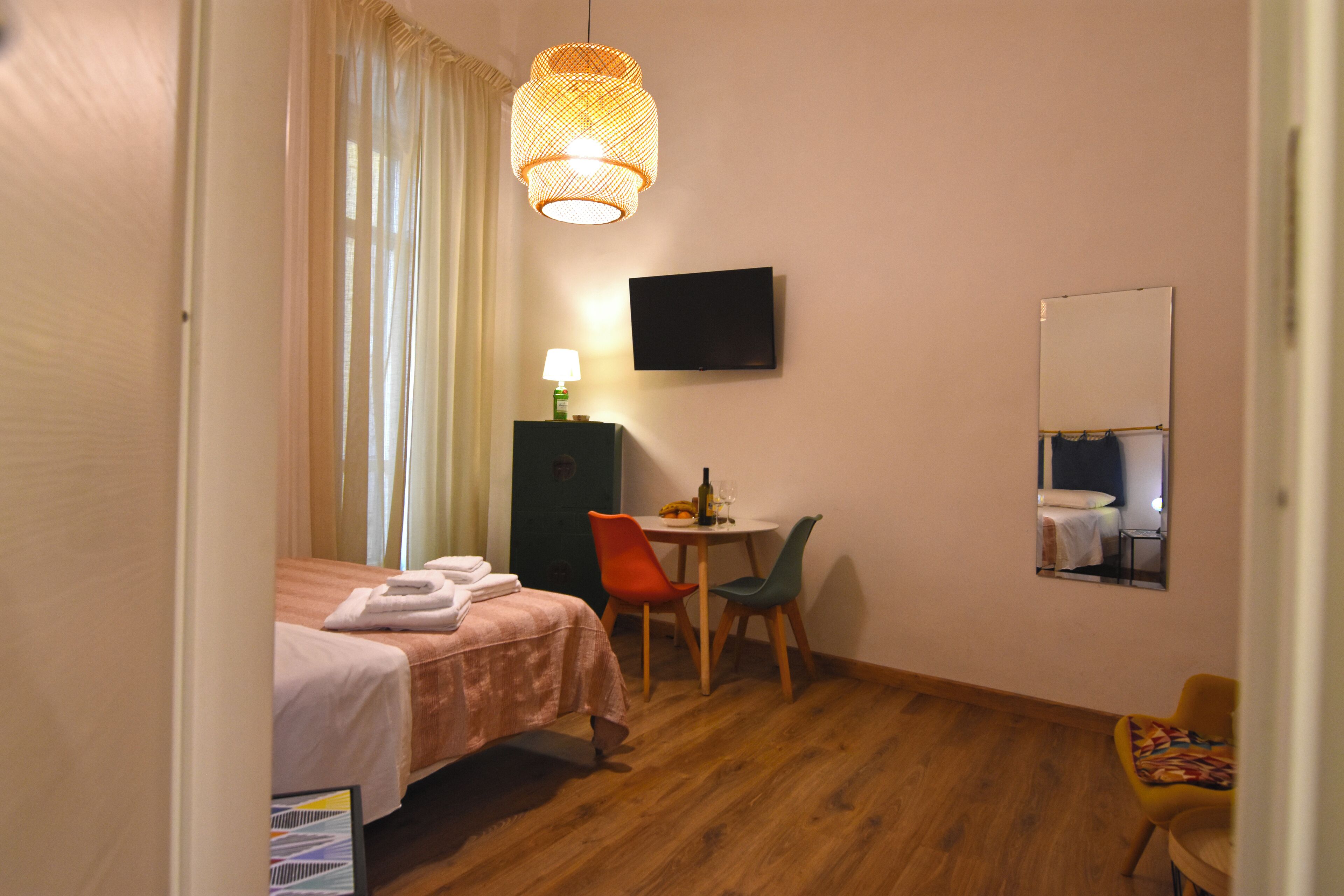 A hotel room with a bed, a desk with a chair, a television, and a mirror.